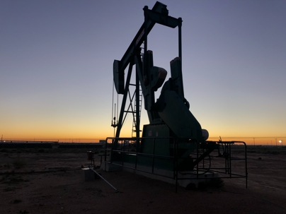 silhouette of natural gas pump jack at sunset