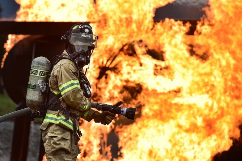 firefighter putting out a house fire with a hose